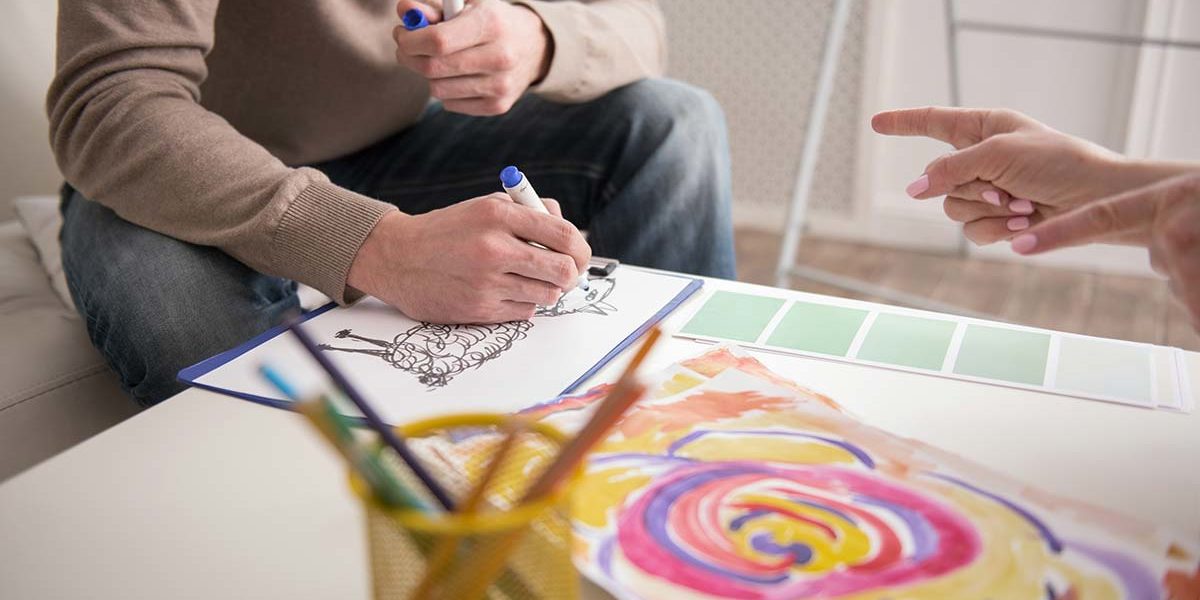 man coloring and showing work to therapist during art therapy in florida