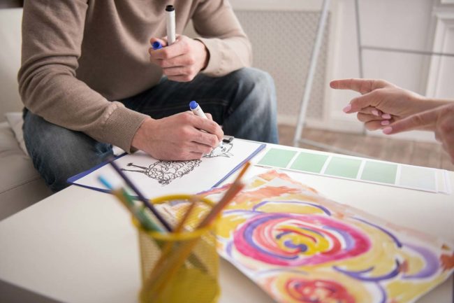 man coloring and showing work to therapist during art therapy in florida