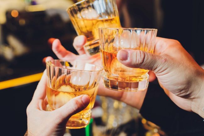 glasses of alcohol clinking in an addiction enabling toast