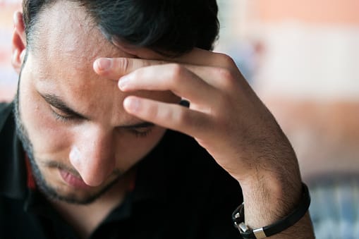 Man with hand on forehead has gotten into trouble with his addictive behaviors.
