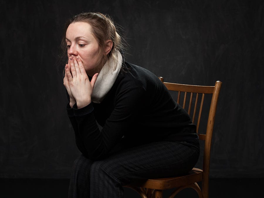 Woman sitting on chair in dark looking for a women's drug rehab