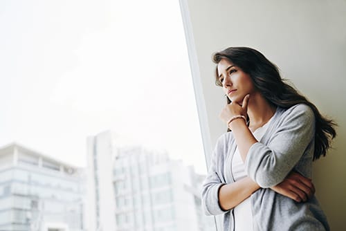 Woman at window with hand to chin thinking about how to find the best Florida detox center