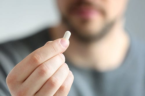 Man holding up detox drugs used for addiction recovery.