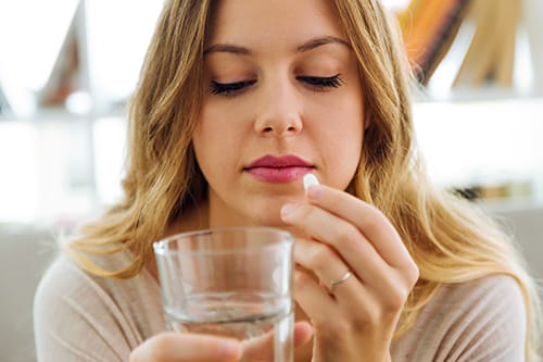 Girl taking a pill may need adderall addiction treatment