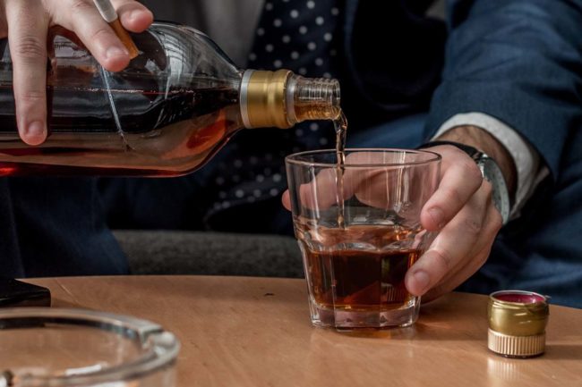 close up of middle aged businessman pouring alcohol risking alcohol and blood pressure