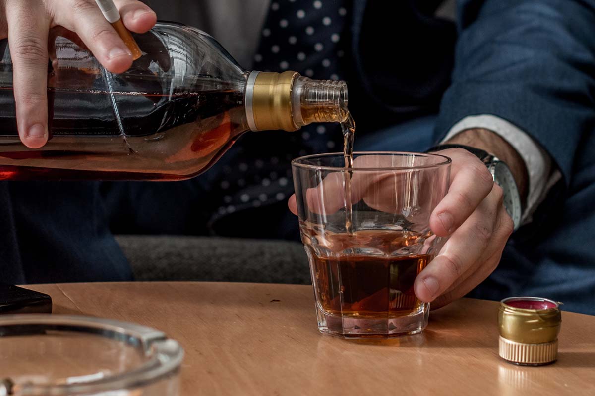 close up of middle aged businessman pouring alcohol risking alcohol and blood pressure