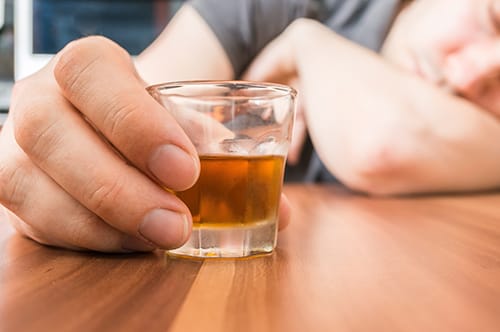 Person holding shot glass may want to know alcohol detox timeline.