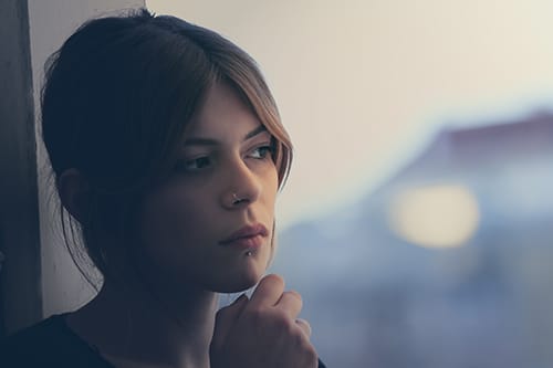 Woman in dark by window wondering about crystal meth detox