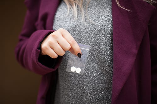 Woman holding small baggie of designer drugs.