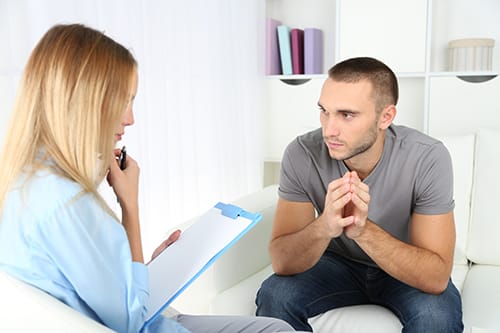 Intake counselor talking to a young man about drug addiction detox.