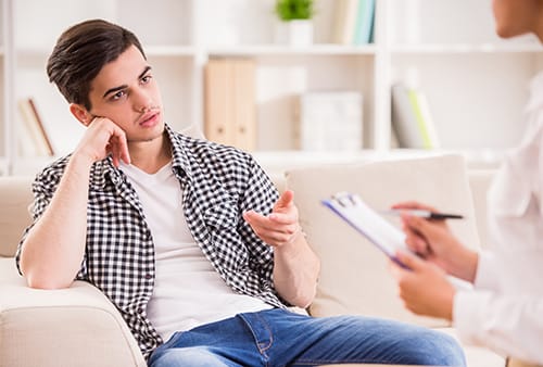 Young man talking to out of picture substance abuse counselor during detox.