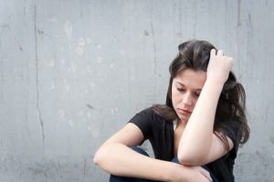 Distressed woman against wall with hangover wants to fix her physical addiction