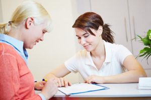Woman signing in to a rehab for women, with the guidance of a counselor.