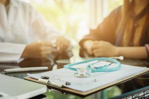 Clip board and stethoscope with people talking about medical drug detox