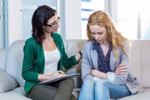 Depressed woman on couch talking to therapist about bipolar disorder treatment