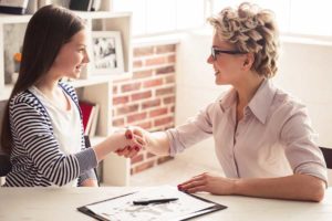 Two young women shaking hands over crystal meth addiction treatment discussion