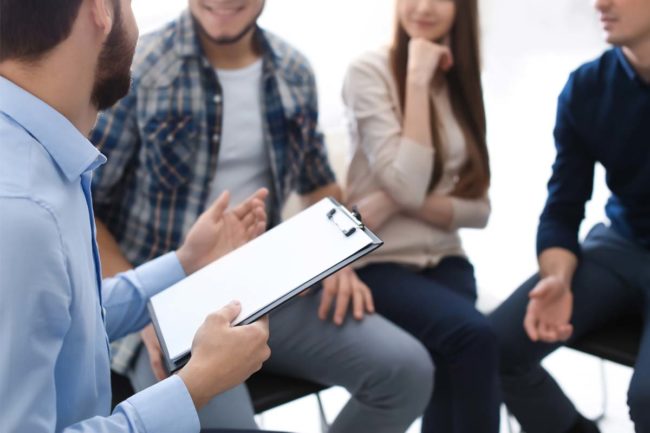 man leading group therapy for addiction treatment going over emotions and addiction recovery