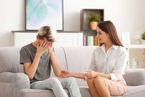 Two people on sofa, young man needing behavioral health services