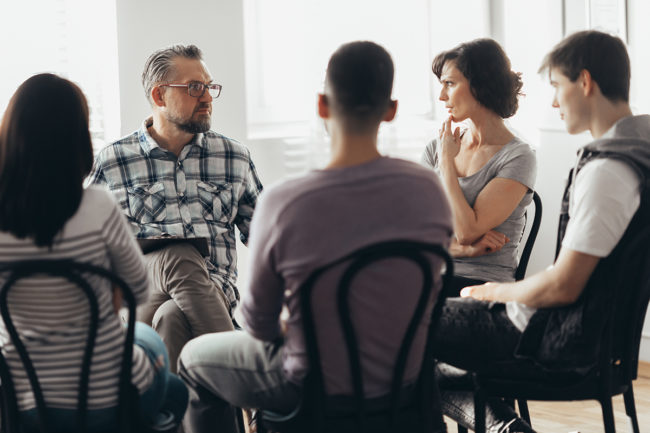 a group therapy session discussing cost of rehab