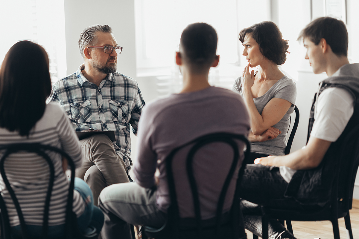a group therapy session discussing cost of rehab