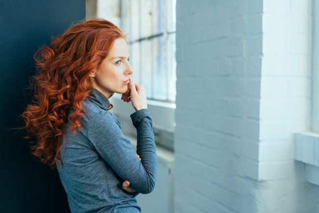 woman looking out the window wondering what is chronic relapse