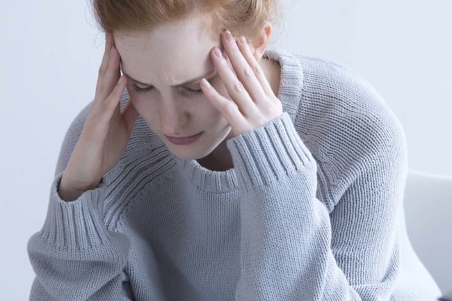 woman with headache struggling with the signs of ptsd