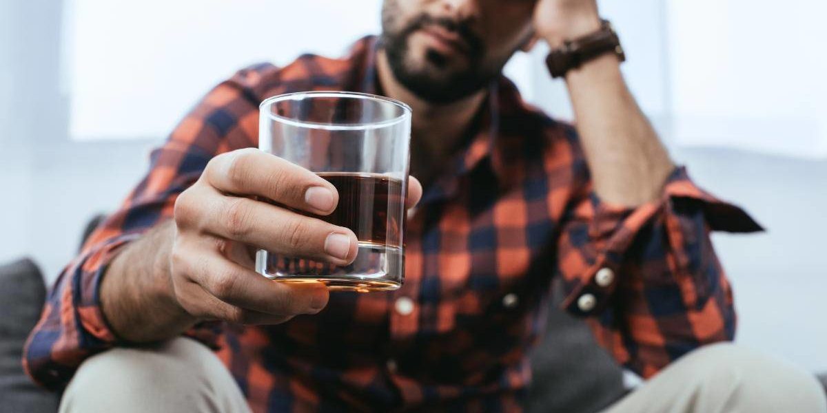 a man drinking alcohol thinking about the history of alcoholism