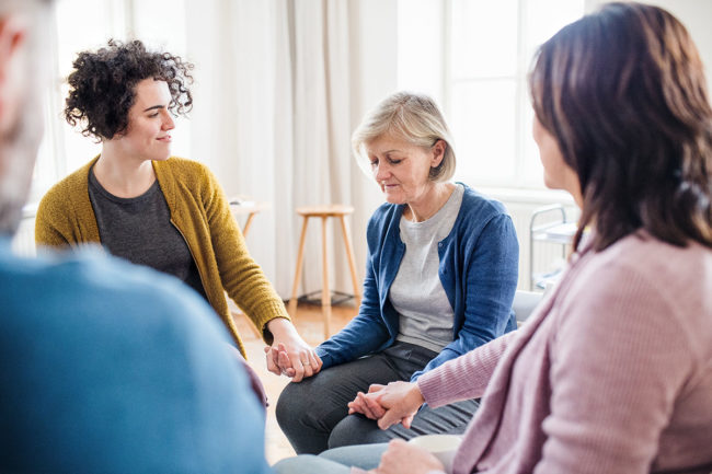 a woman holding hands at a steps to recovery meeting