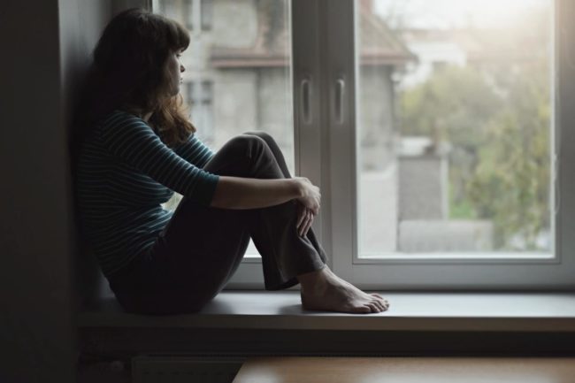 a woman looking out her window struggling with bipolar disorder and addiction