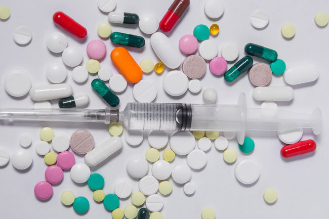 a needle on top of a pile of opiate drugs