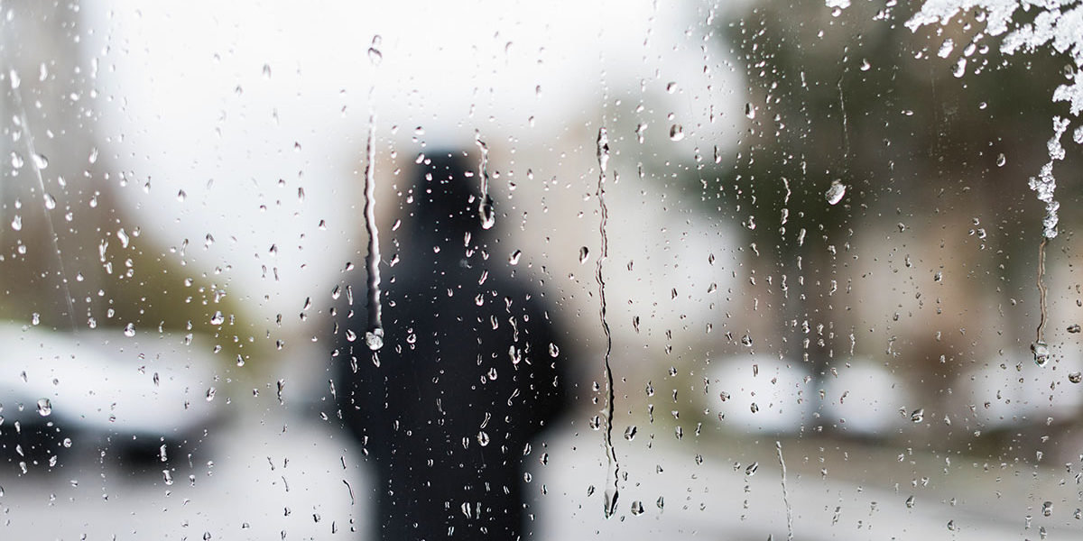 a person walking in the rain struggling with the signs of seasonal depression
