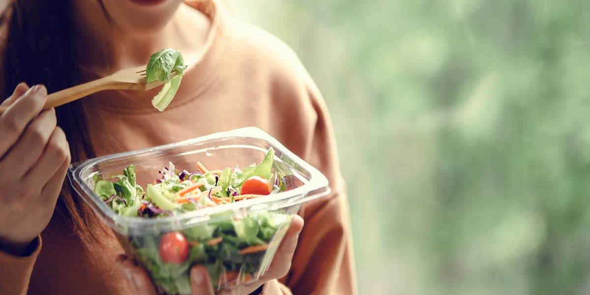 woman enjoys a salad, which aids her detox
