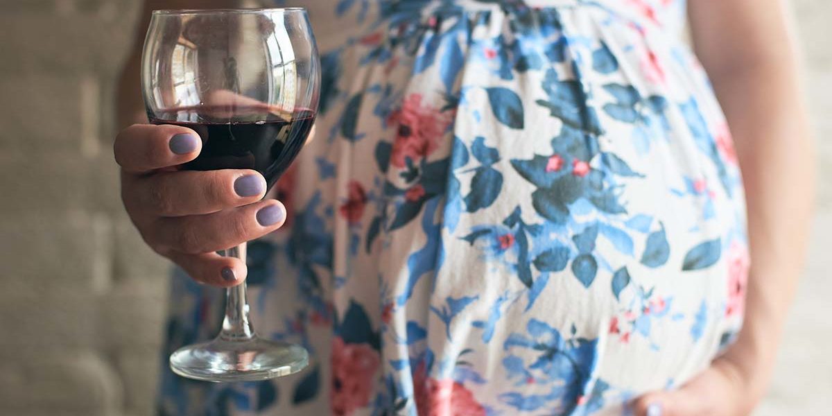 a woman debates drinking wine while pregnant