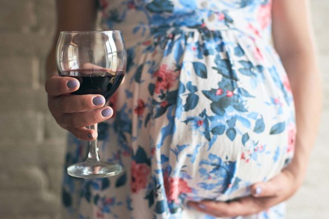a woman debates drinking wine while pregnant