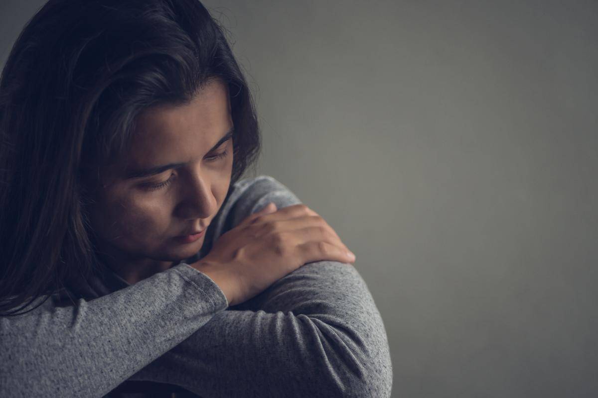 someone hunched over suffering from bipolar disorder triggers